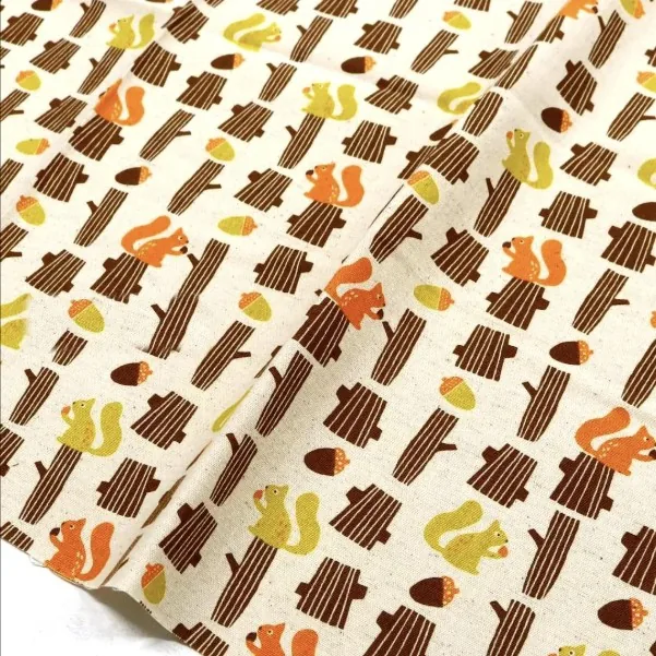 Cream linen-blend canvas printed with orange squirrels, acorns and tree stumps