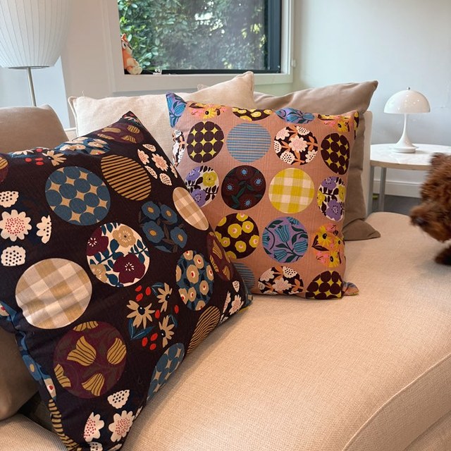 Two Atelier Dorothy cushion covers with patterned circles on a cream sofa by a window