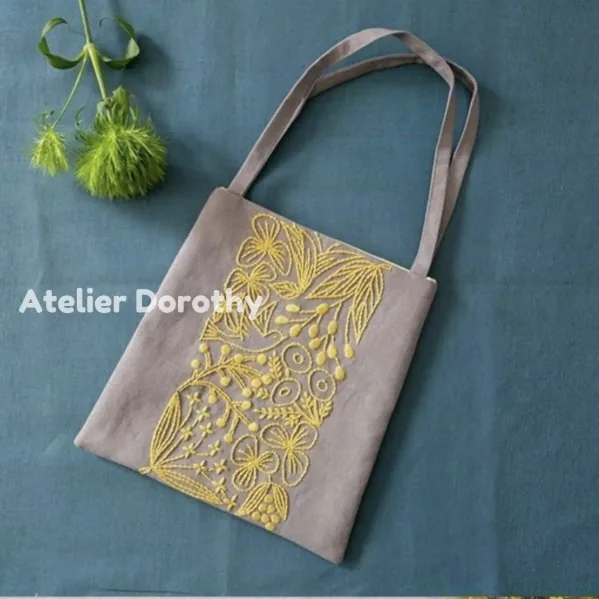 Gray linen tote bag embroidered with yellow birds and wildflowers