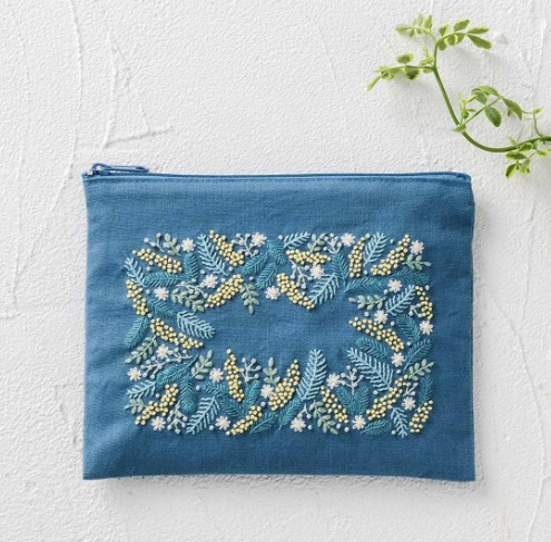 Blue zip pouch embroidered with a mimosa and leaf border