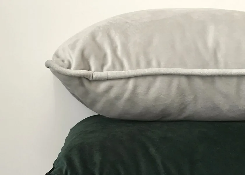 Soft velvet cushions stacked against a pale wall